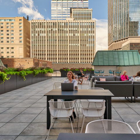 a group of people sitting around a table on a workbox down town roof