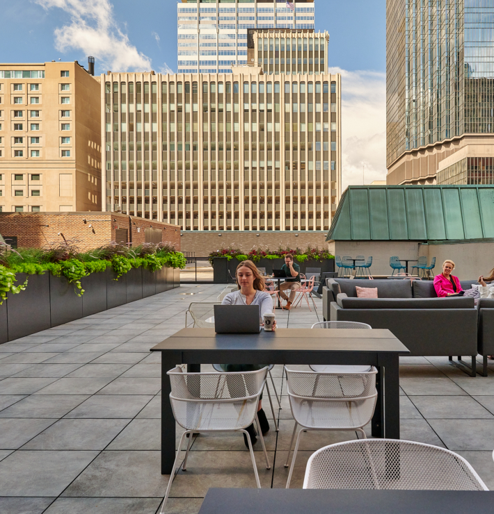 a group of people sitting around a table on a workbox down town roof