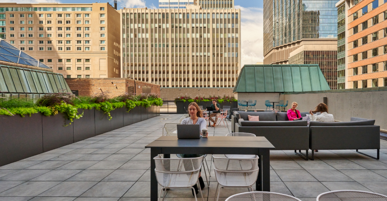 a group of people sitting around a table on a workbox down town roof