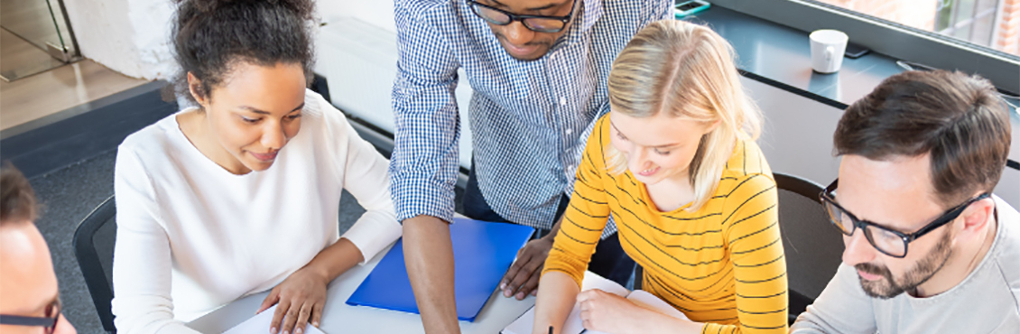 group of people sitting around a table working on papers