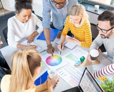 group of people sitting around a table working on papers