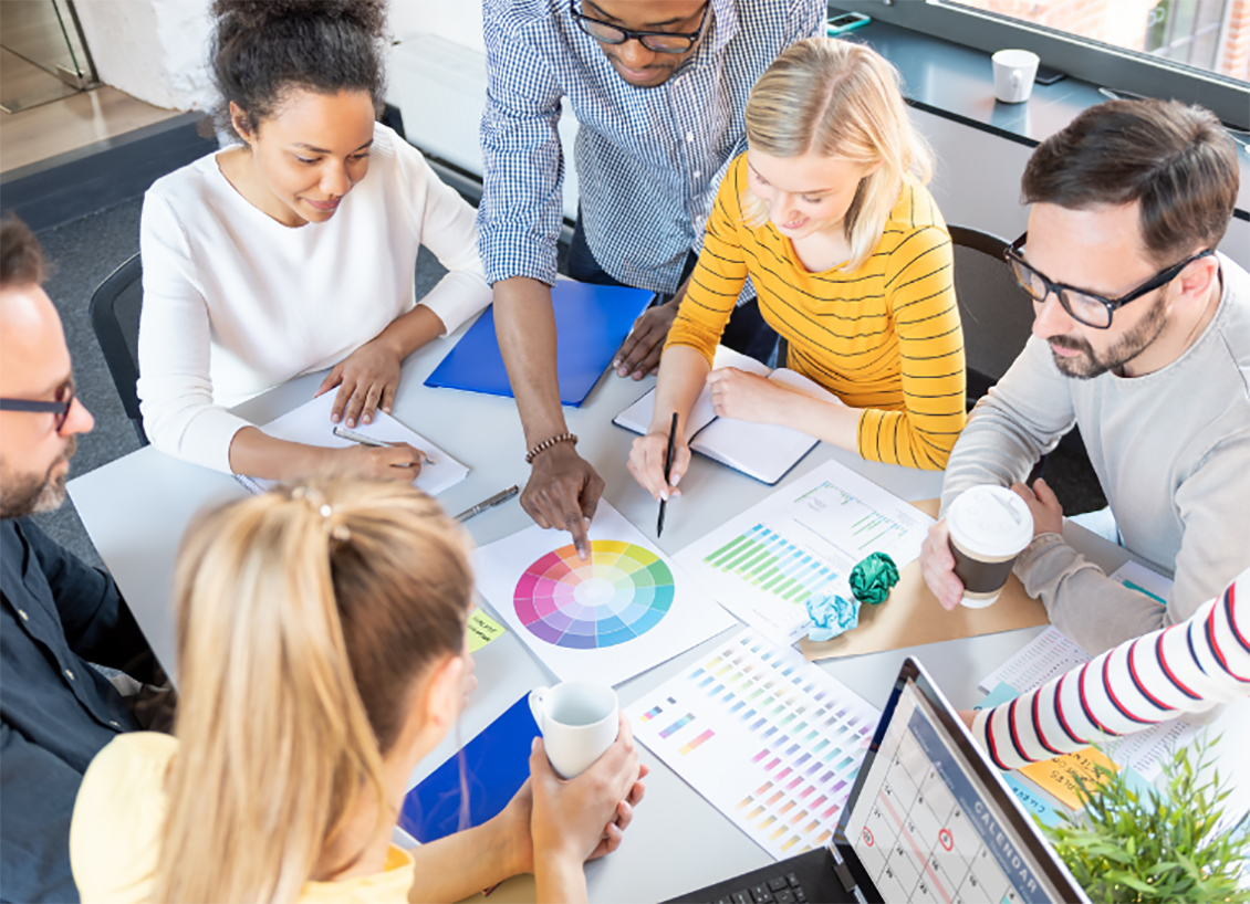 group of people sitting around a table working on papers